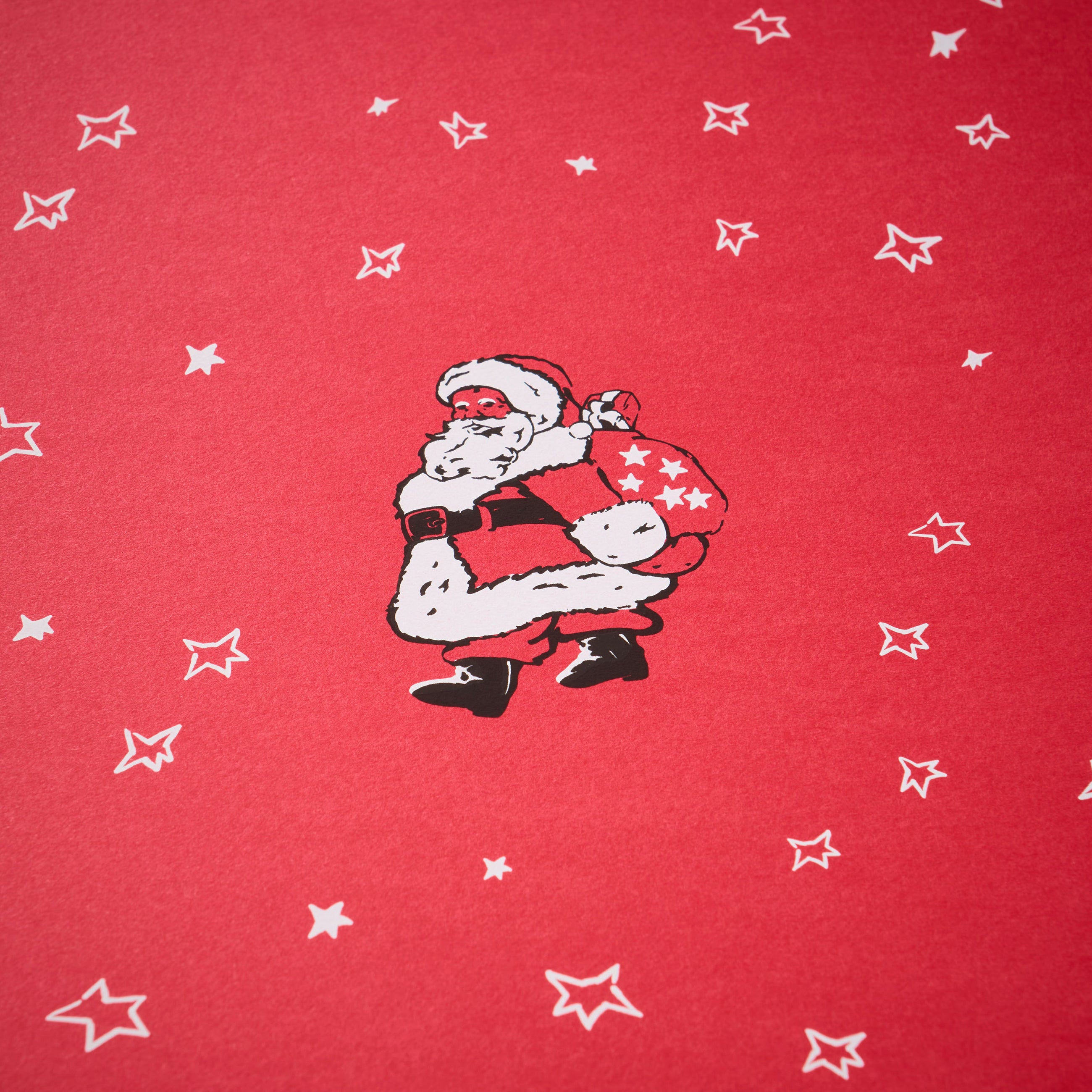 Wrapping paper with a festive pattern of a vintage-style Santa carrying a star-covered sack, surrounded by scattered white hand-drawn stars on a bright red background.
