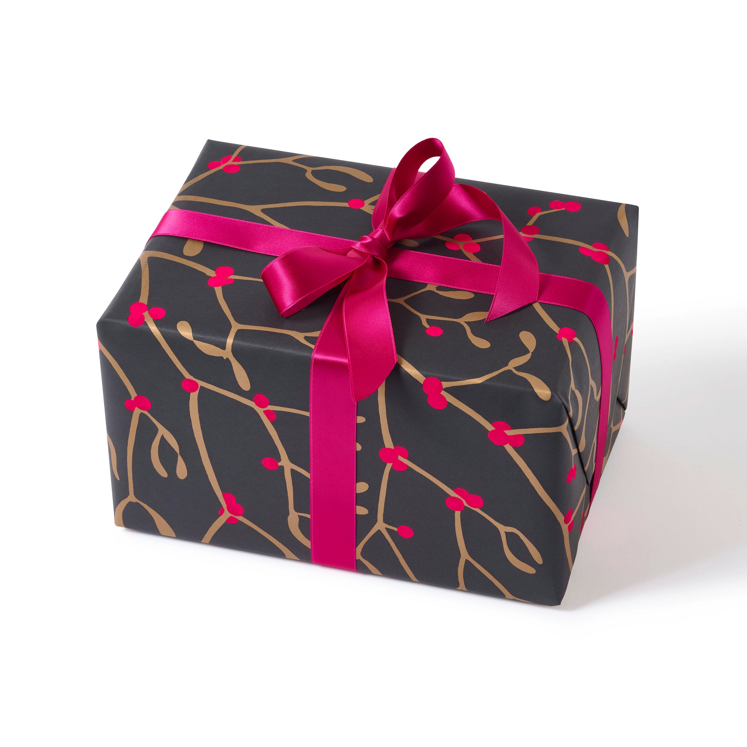 A gift wrapped in festive paper featuring golden mistletoe branches on a deep charcoal background, tied with a vibrant pink satin ribbon.