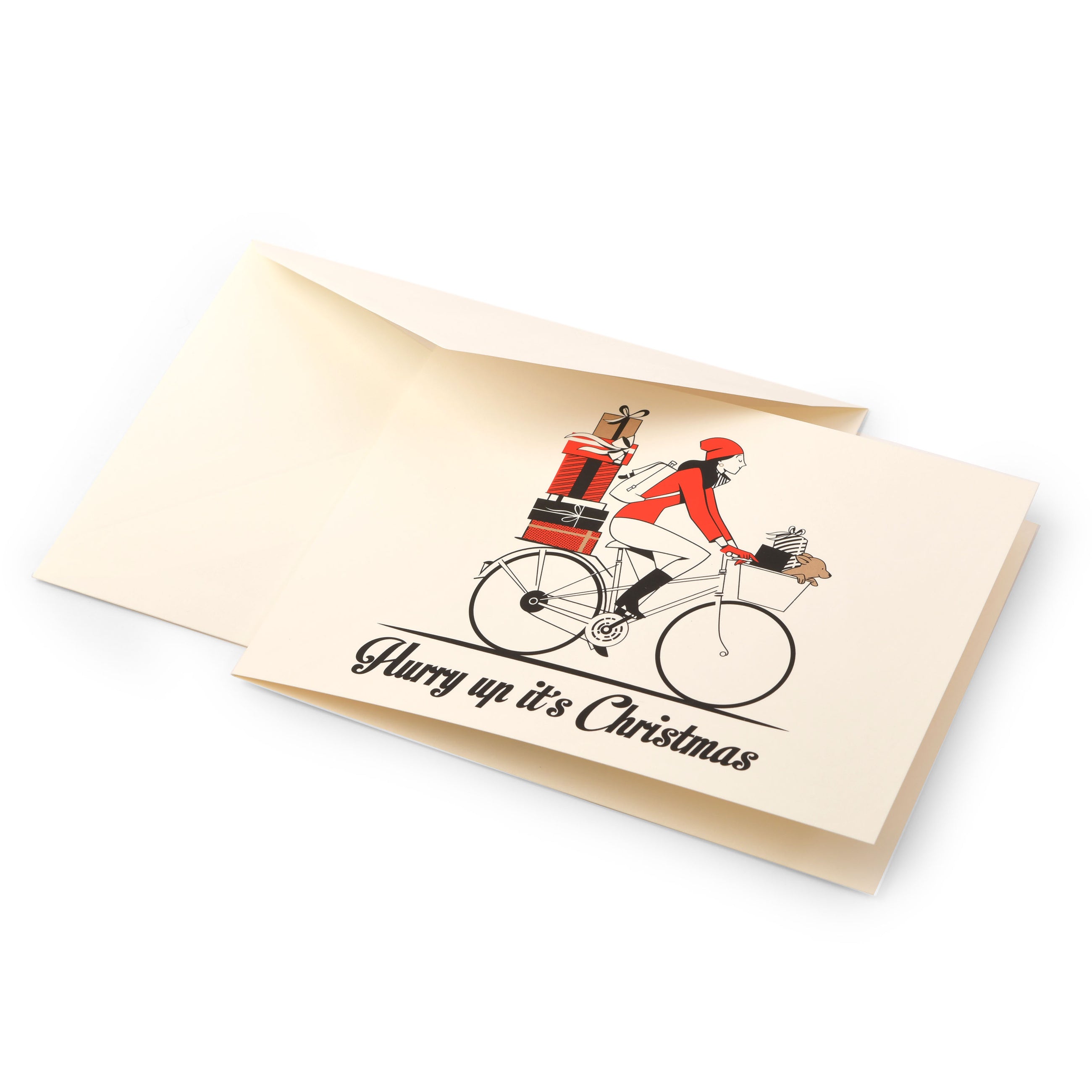 A cream-colored Christmas card featuring an illustration of a woman in a red hat and coat riding a bicycle stacked with presents, with more gifts in the front basket, and the text "Hurry up it's Christmas" in black at the bottom, shown with a matching cream envelope.
