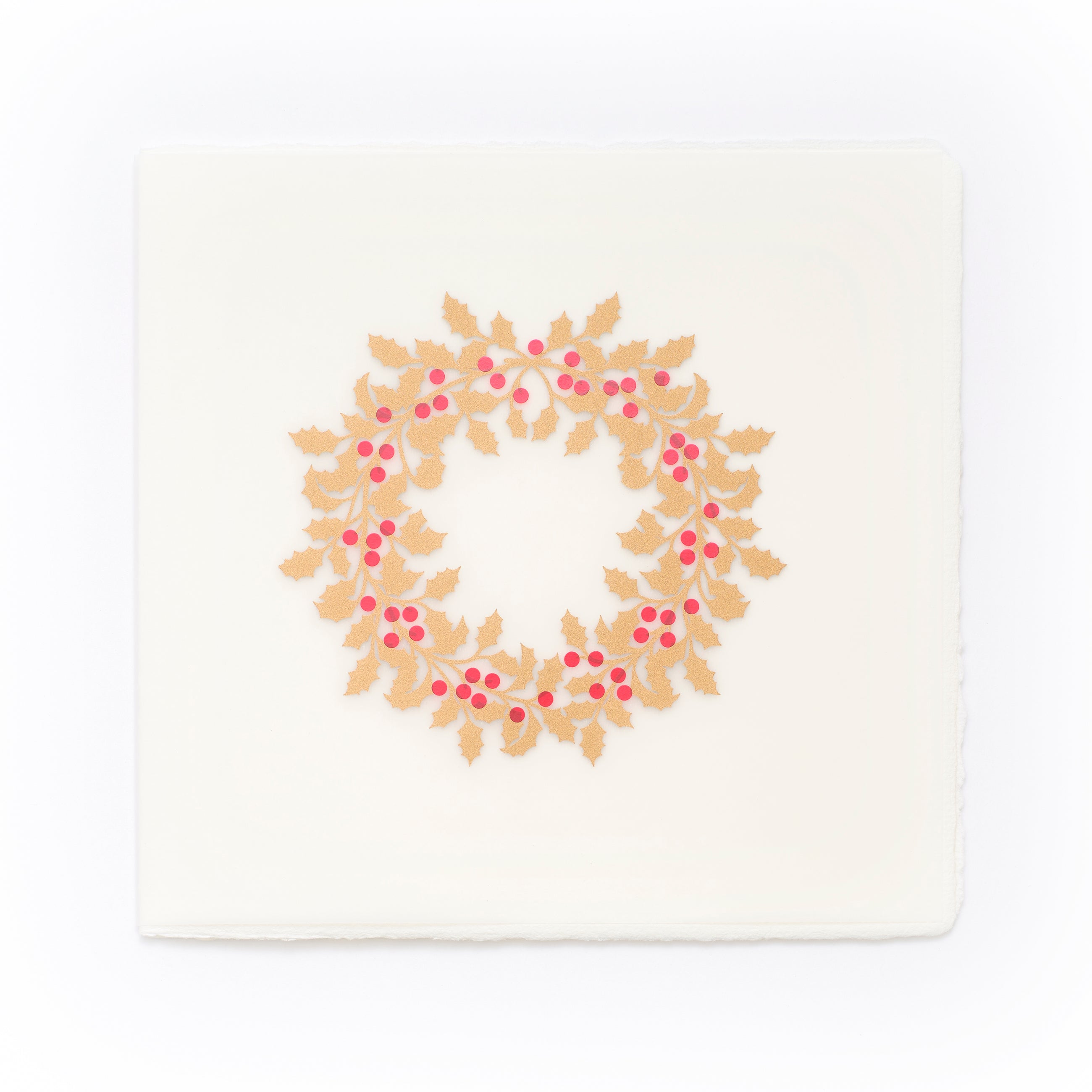 A cream-colored Christmas card with deckled edges, featuring a festive holly wreath design made of gold leaves and bright red berries.