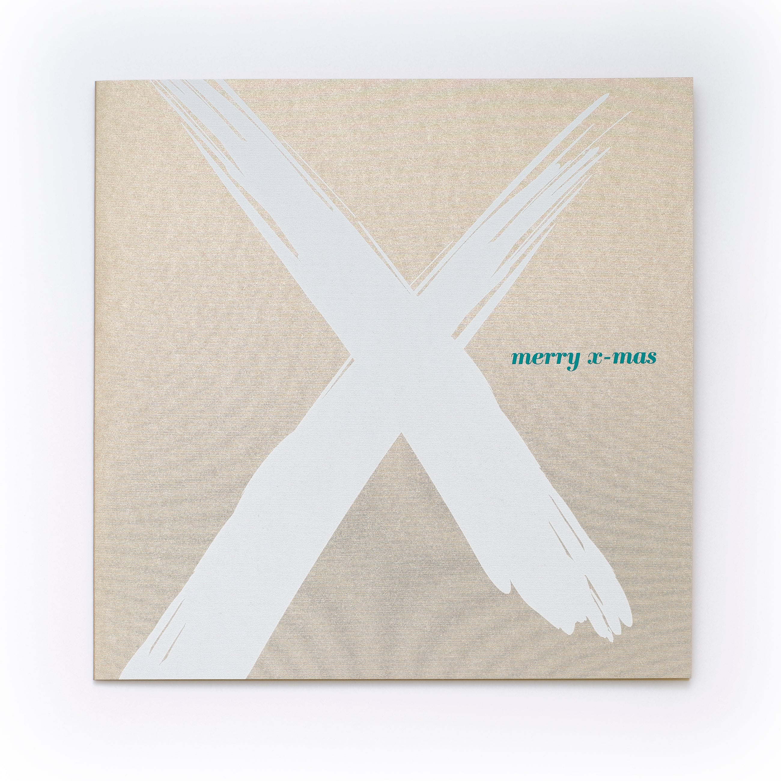 Christmas card with a bold white brushstroke “X” on a gold background and the text “merry x-mas” in small green letters.