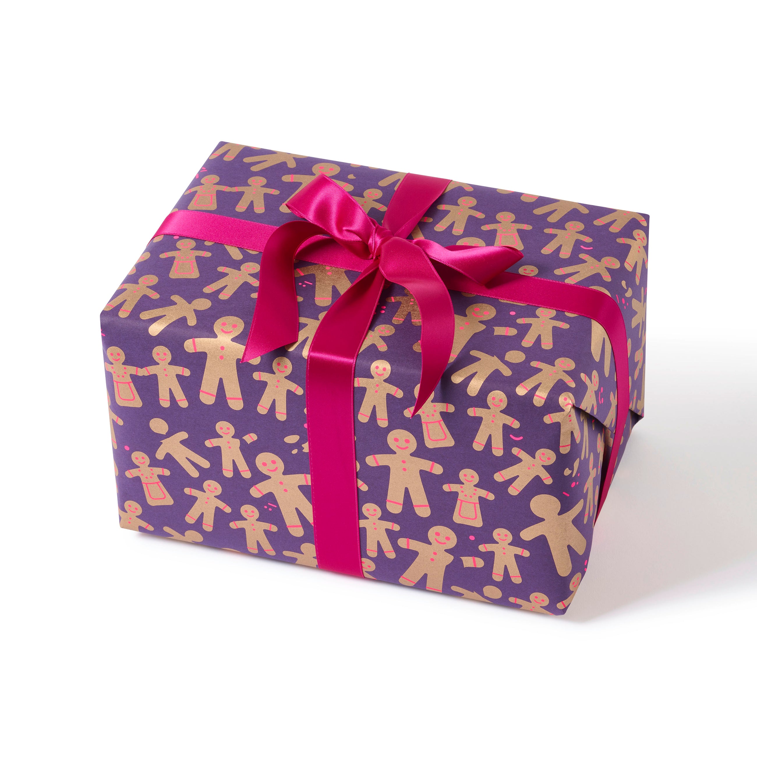 A gift wrapped in festive paper decorated with golden gingerbread men and women on a deep purple background, finished with a vibrant pink satin ribbon.