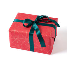 Wrapped gift with a festive pattern of golden star outlines on a deep red background, tied with a dark teal satin ribbon.
