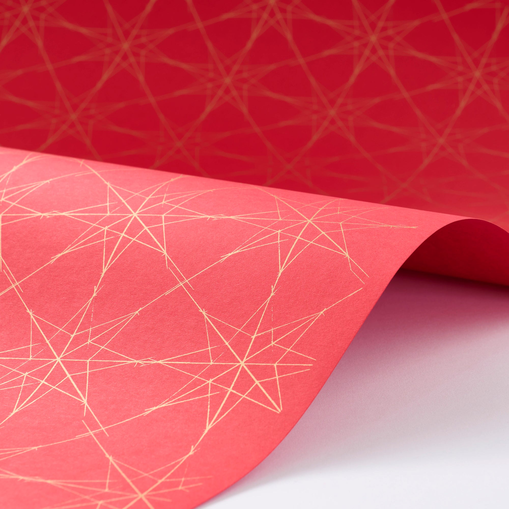 Wrapping paper with a festive pattern of tiny white stars dotted across a bright red background.