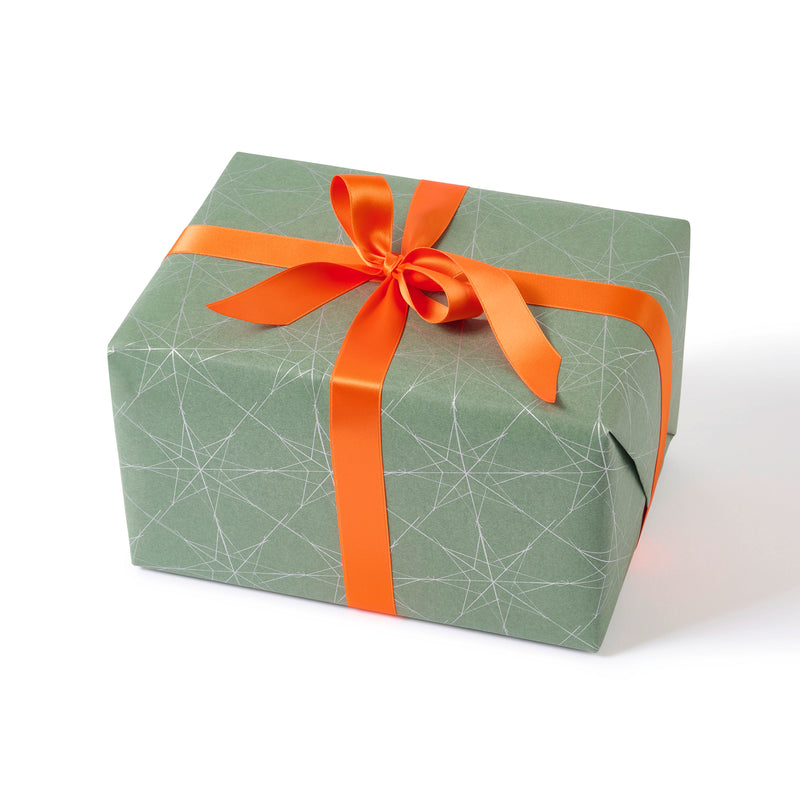 A gift wrapped in sage-green paper with a festive pattern of white star outlines and tied with a bright orange satin ribbon.