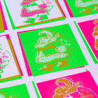 Close-up of colorful wrapping paper featuring a pop art Santa Claus design in neon pink, green, and gold tones with a halftone print effect.