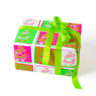 Gift wrapped in vibrant pop art Santa Claus paper with neon pink, green, and gold squares, tied with a bright green satin ribbon and bow.