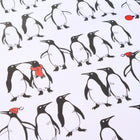 Wrapping paper with a playful pattern of black-and-white penguins on a crisp white background, with a few penguins accented by bright red scarves or hats for a festive touch.