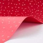 Wrapping paper with a festive pattern of tiny white sketchy stars scattered across a vivid red background.