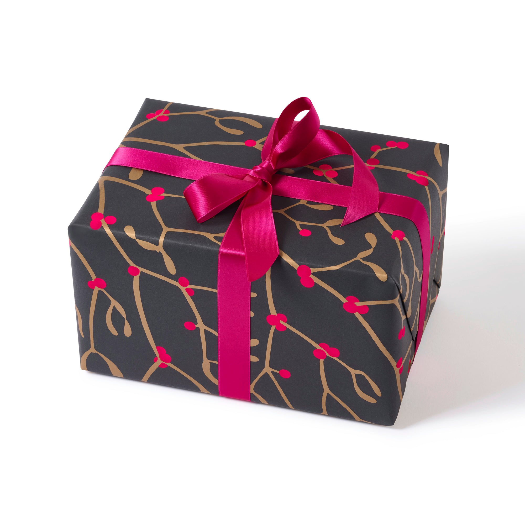 A gift wrapped in festive paper featuring golden mistletoe branches on a deep charcoal background, tied with a vibrant pink satin ribbon.