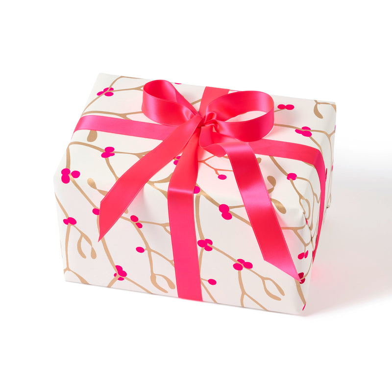 Gift wrapped in paper with a festive pattern of golden mistletoe branches and vibrant pink berries, tied with a wide, glossy pink ribbon.