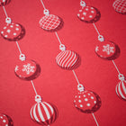 Wrapping paper with a festive pattern of red Christmas baubles decorated in white snowflakes, stripes, grids, and polka dots, arranged in vertical lines against a bright red background.