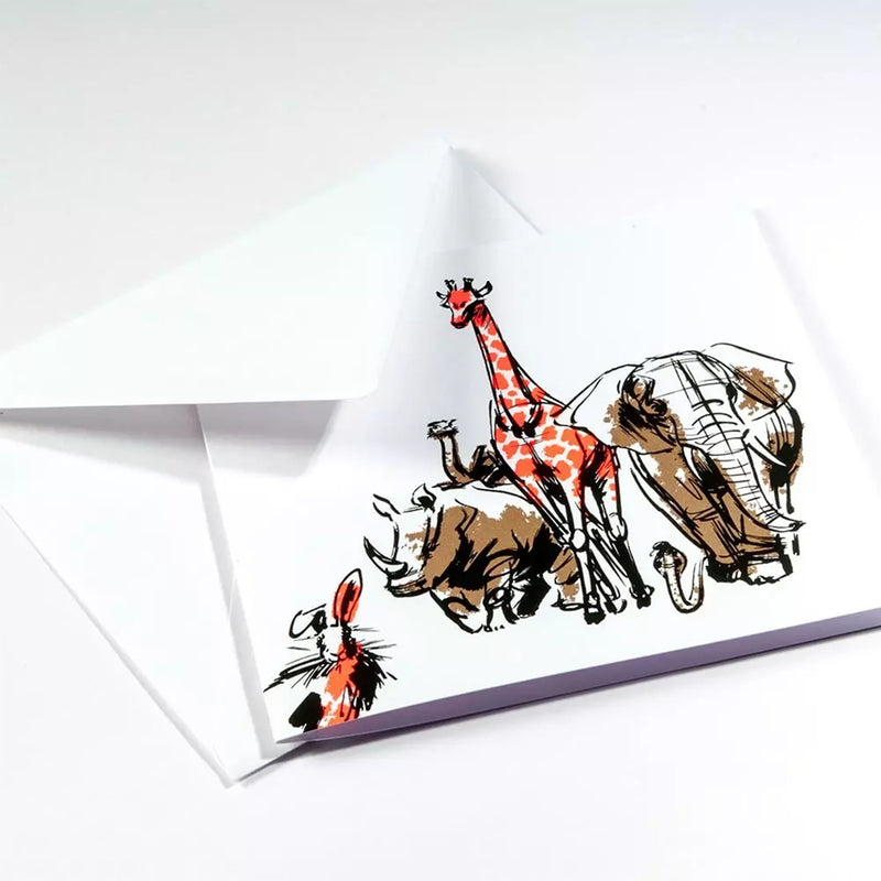 A greeting card partially tucked into a white envelope, showing a lively sketch of safari animals with expressive linework and striking red highlights against a clean white background.