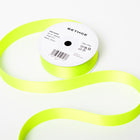 A spool of satin ribbon in neon green, partially unrolled, with a white label on top reading “BETHGE” and product details including width, length, and material.