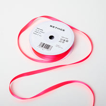 A spool of satin ribbon in neon pink, narrow in width, partially unrolled, with a white label on top reading “BETHGE” and product details including width, length, and material.