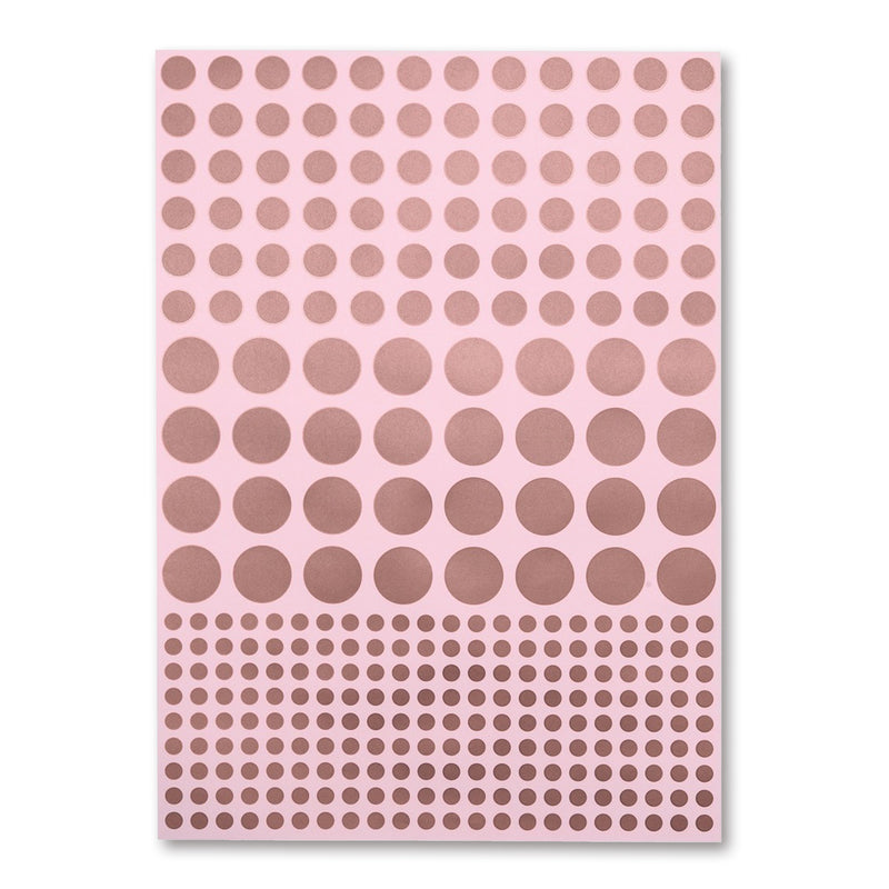 A soft pink sheet of wrapping paper covered in neat rows of metallic copper dots, arranged from medium to large to small for a subtle gradient effect.