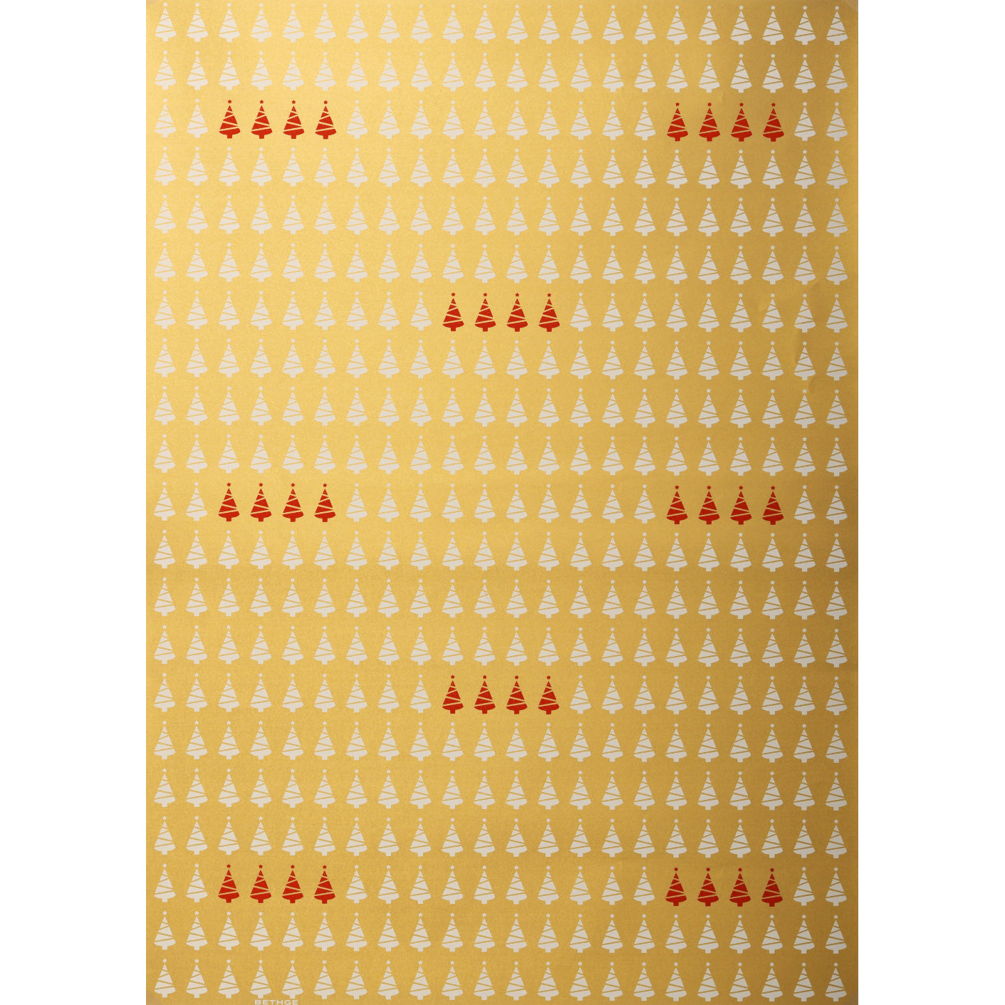 Gold wrapping paper patterned with rows of small white Christmas trees and clusters of red trees scattered throughout.