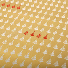 close up of gold wrapping paper patterned with rows of small white Christmas trees and clusters of red trees scattered throughout.