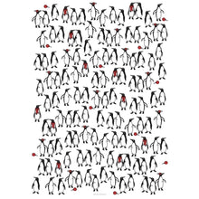 White wrapping paper patterned with groups of illustrated penguins, some wearing red scarves or earmuffs and others holding red ornaments, creating a playful festive design.