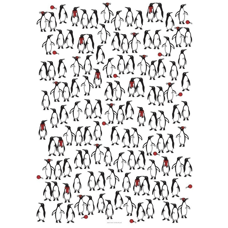 White wrapping paper patterned with groups of illustrated penguins, some wearing red scarves or earmuffs and others holding red ornaments, creating a playful festive design.