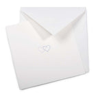 A soft ivory greeting card partly pulled from a matching envelope, featuring two fine-line hearts in blue and lilac printed at the center.
