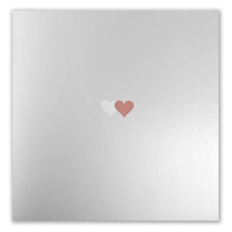 Greeting card with a minimalist design, featuring a smooth mirror-like silver finish and a pair of tiny overlapping hearts in white and bronze placed at the center, presented flat to emphasize the subtle sheen and refined metallic texture.