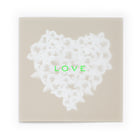 Greeting card with an elegant, understated design, featuring a textured white feather heart centered on a warm beige background, accented by bright neon-green “LOVE” text, shown flat against a clean white backdrop.