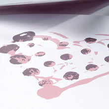 Greeting card with a minimalist design, featuring a hand-stamped heart made of soft pink and muted purple dots, shown in a close-up view with gentle shadows and the envelope partially open above it.
