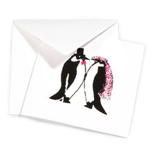 A folded greeting card shown with its envelope, featuring the same penguin wedding illustration centered on the front.