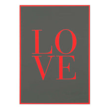 A flat-lay view of a dark grey greeting card featuring the word “LOVE” in large red letters, framed by a thin red border against a neutral background.