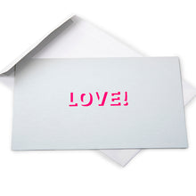 Silver greeting card with a metallic finish and the word “LOVE!” cut out in bright pink, shown with a white envelope behind it.