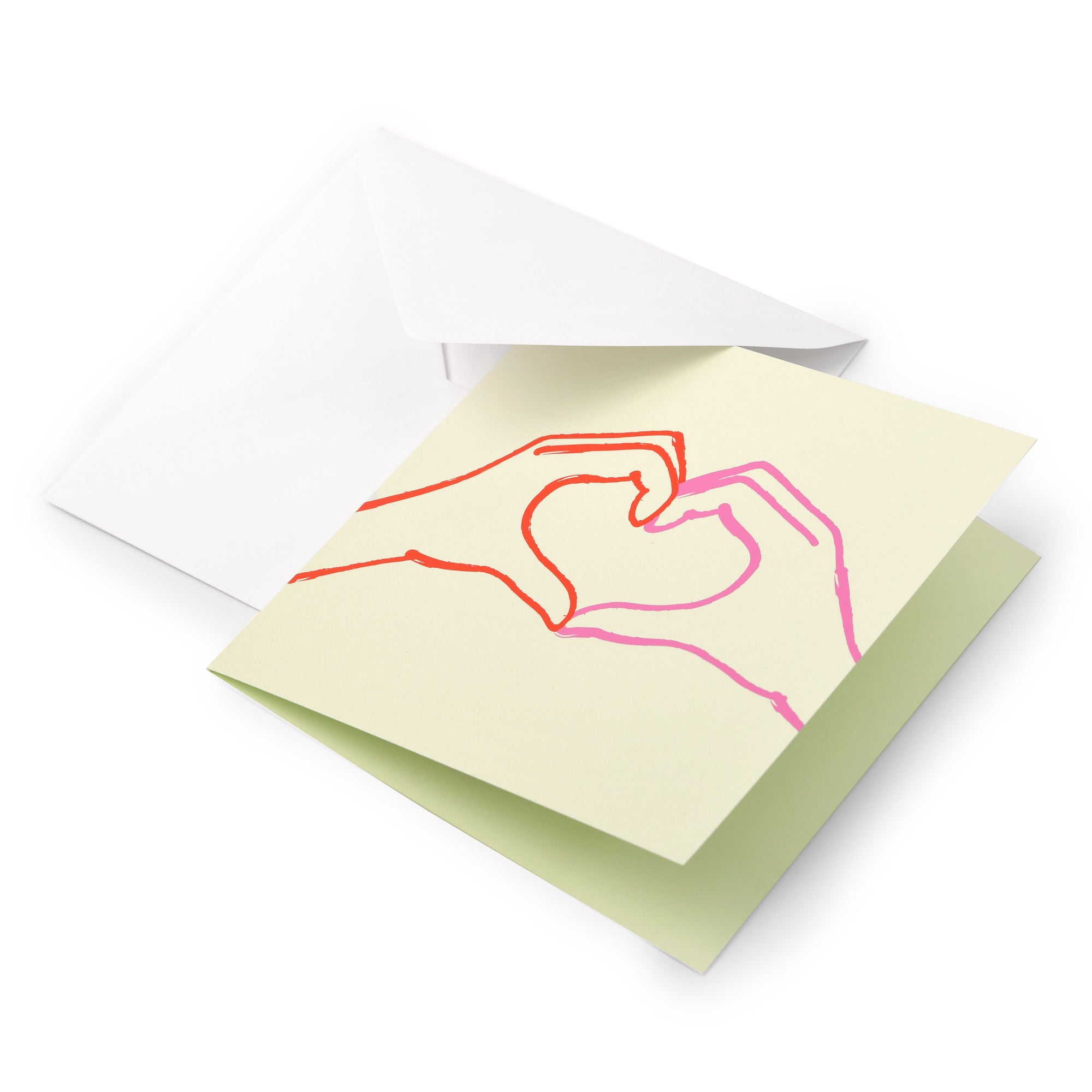 Greeting card with a minimalist line illustration of two hands forming a heart, drawn in red and pink on a soft light-green background, shown partially inside a white envelope.