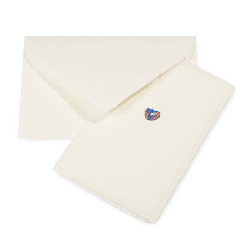 Greeting card with a minimalist design, featuring a tiny blue-and-copper heart on cream handmade paper, shown alongside a matching deckle-edged envelope.
