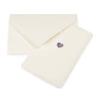 Greeting card with a minimalist design, featuring a tiny blue-and-copper heart on cream handmade paper, shown alongside a matching deckle-edged envelope.