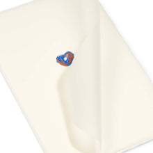 Greeting card with a minimalist design, featuring a tiny hand-painted heart in blue and copper tones on soft cream handmade paper, shown partially open with visible deckle edges.