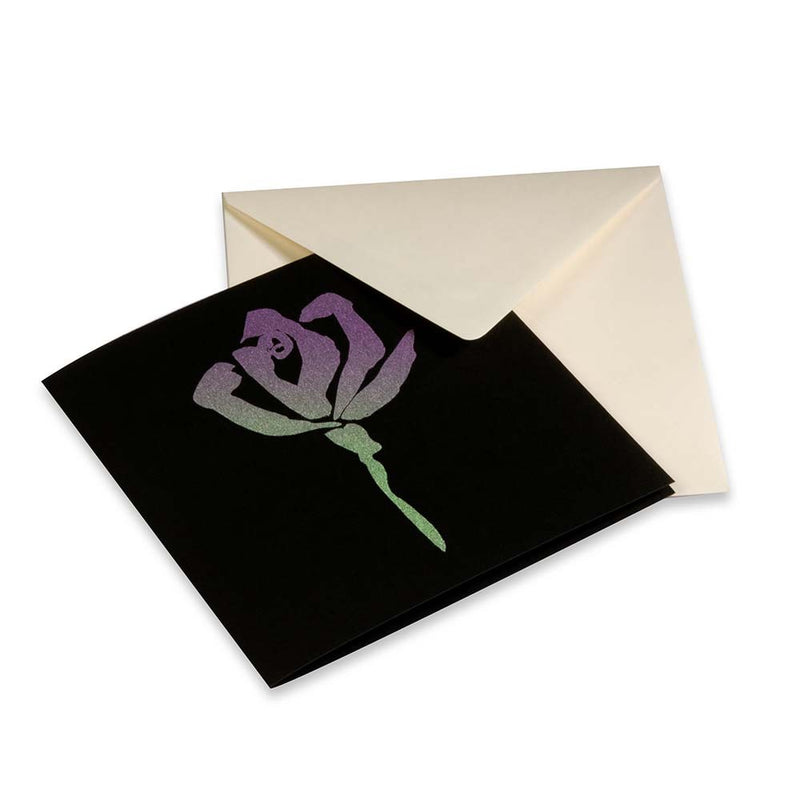 A black greeting card shown at a slight angle, featuring a stylized rose in shimmering purple and green tones, partly pulled from a light-colored envelope.