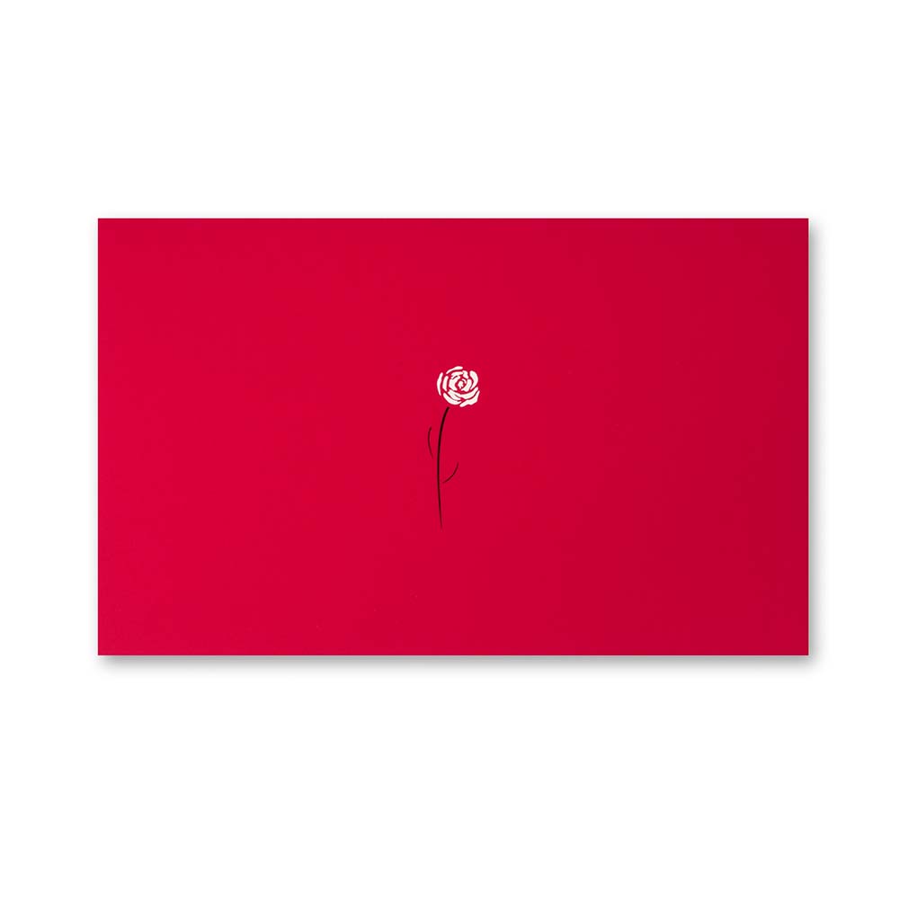 A bright red greeting card featuring a small white rose with a thin black stem printed near the center against the smooth red surface.