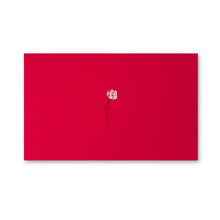A bright red greeting card featuring a small white rose with a thin black stem printed near the center against the smooth red surface.