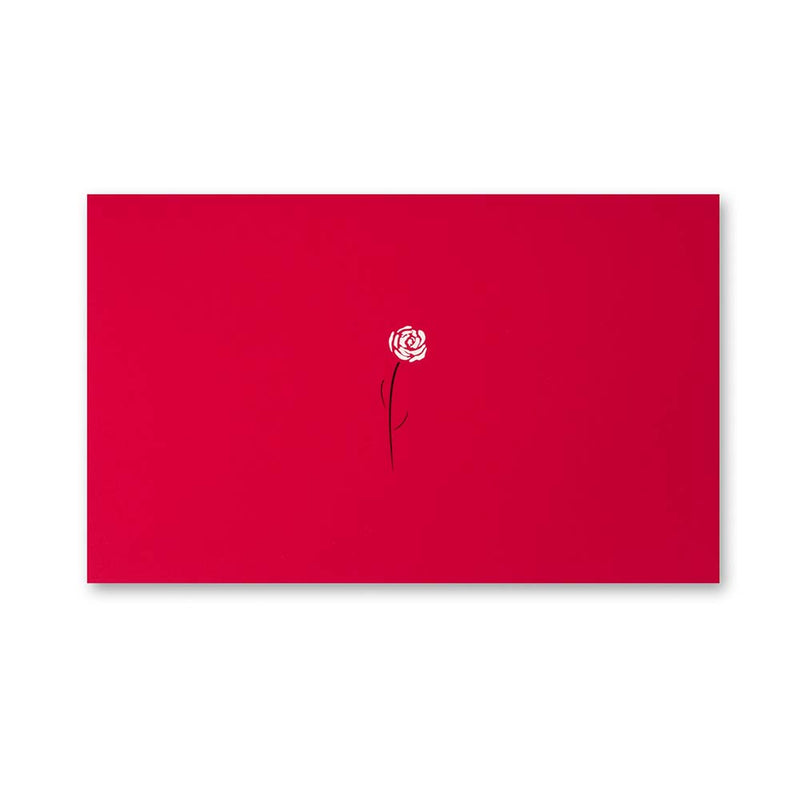 A bright red greeting card featuring a small white rose with a thin black stem printed near the center against the smooth red surface.