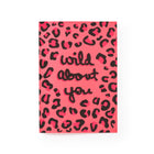 Greeting card displayed upright with a bright pink leopard-print pattern and bold black handwritten-style text reading “wild about you,” centered on the card front.