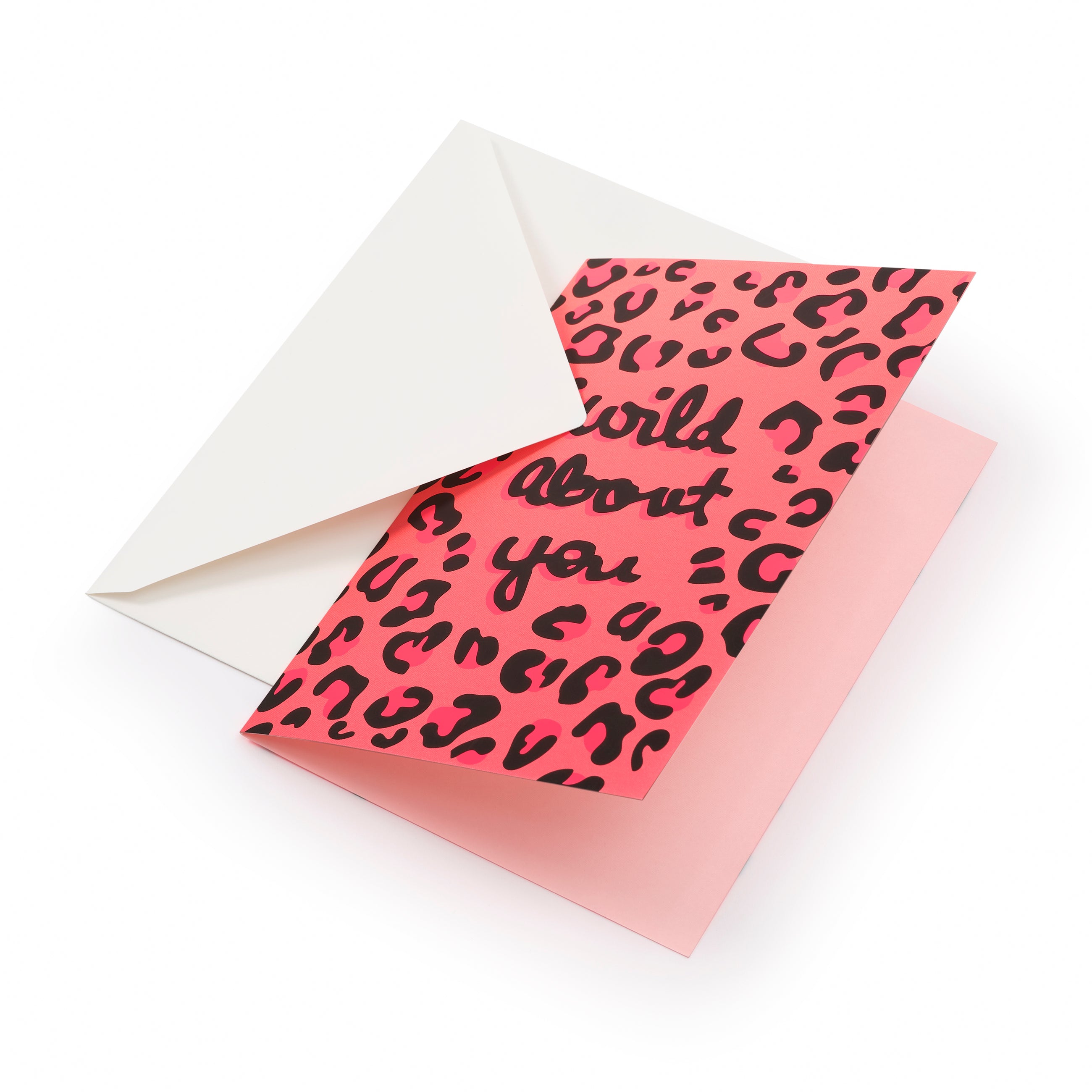Greeting card with a bold pink background covered in a playful black leopard pattern, partially pulled from a white envelope, featuring hand-lettered text that reads “wild about you.”