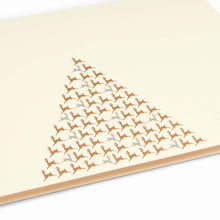 A close-up of an elegant cream Christmas card decorated with a triangular pattern of small gold reindeer forming the shape of a Christmas tree.