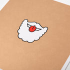 A close-up of a humorous Christmas card with a cartoon illustration of Santa’s white beard and mustache with his red tongue sticking out.