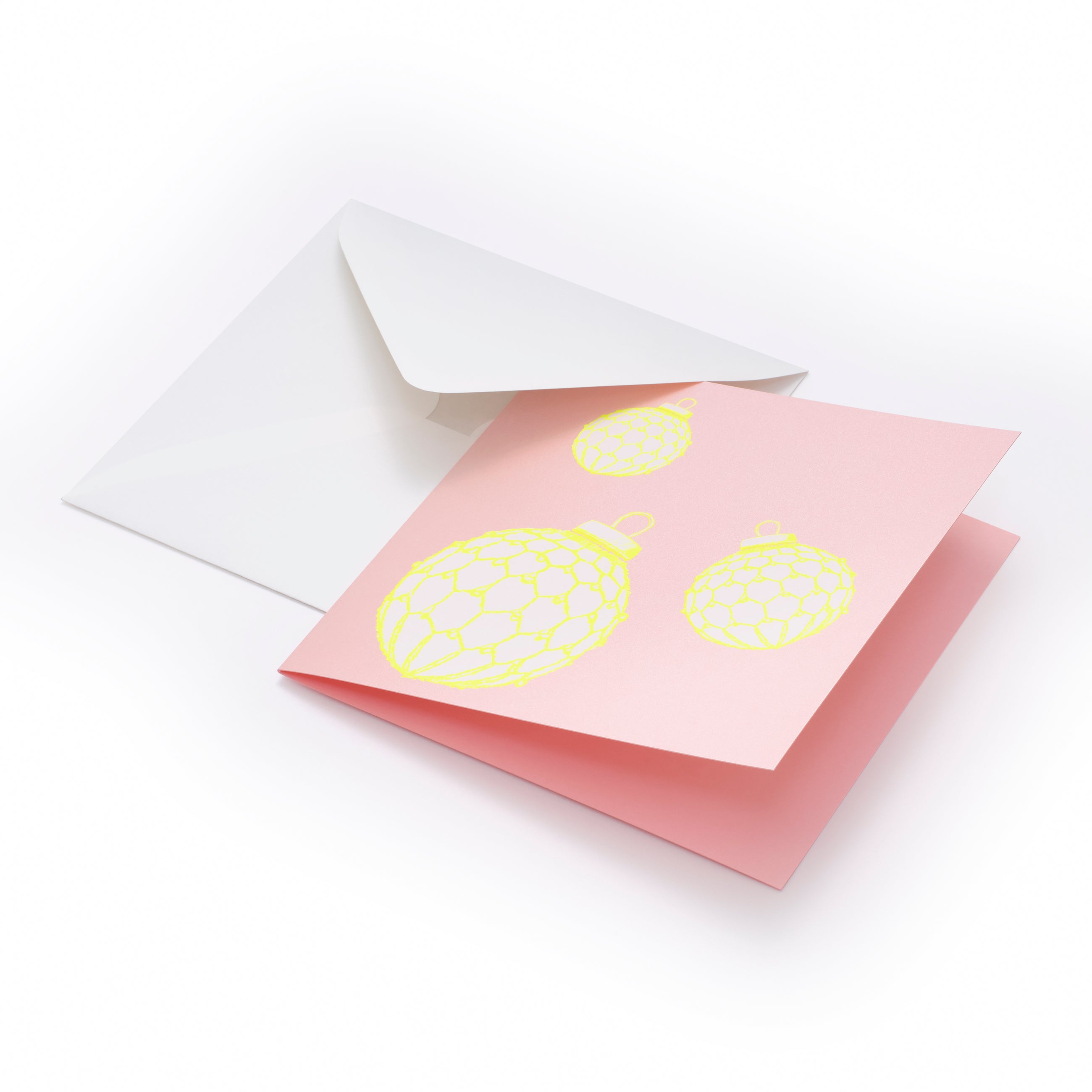 A pastel pink card featuring neon yellow baubles for a fresh and playful holiday design, paired with a white envelope.