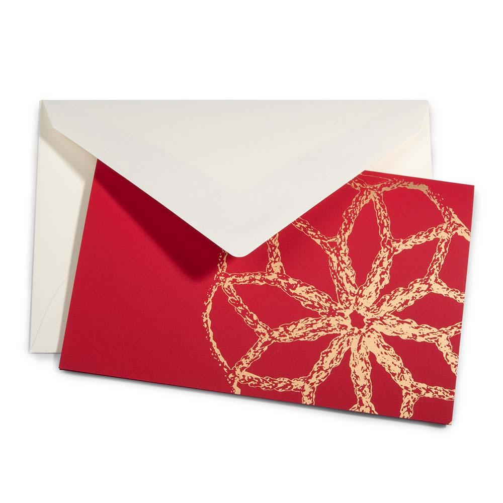 A Christmas card with a large golden bauble design on a bright red background, paired with a cream envelope.