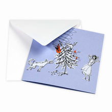 Humorous Christmas card on a light blue background showing a toppled Christmas tree, a playful dog, and a shocked woman reacting to the chaos, paired with a plain white envelope.