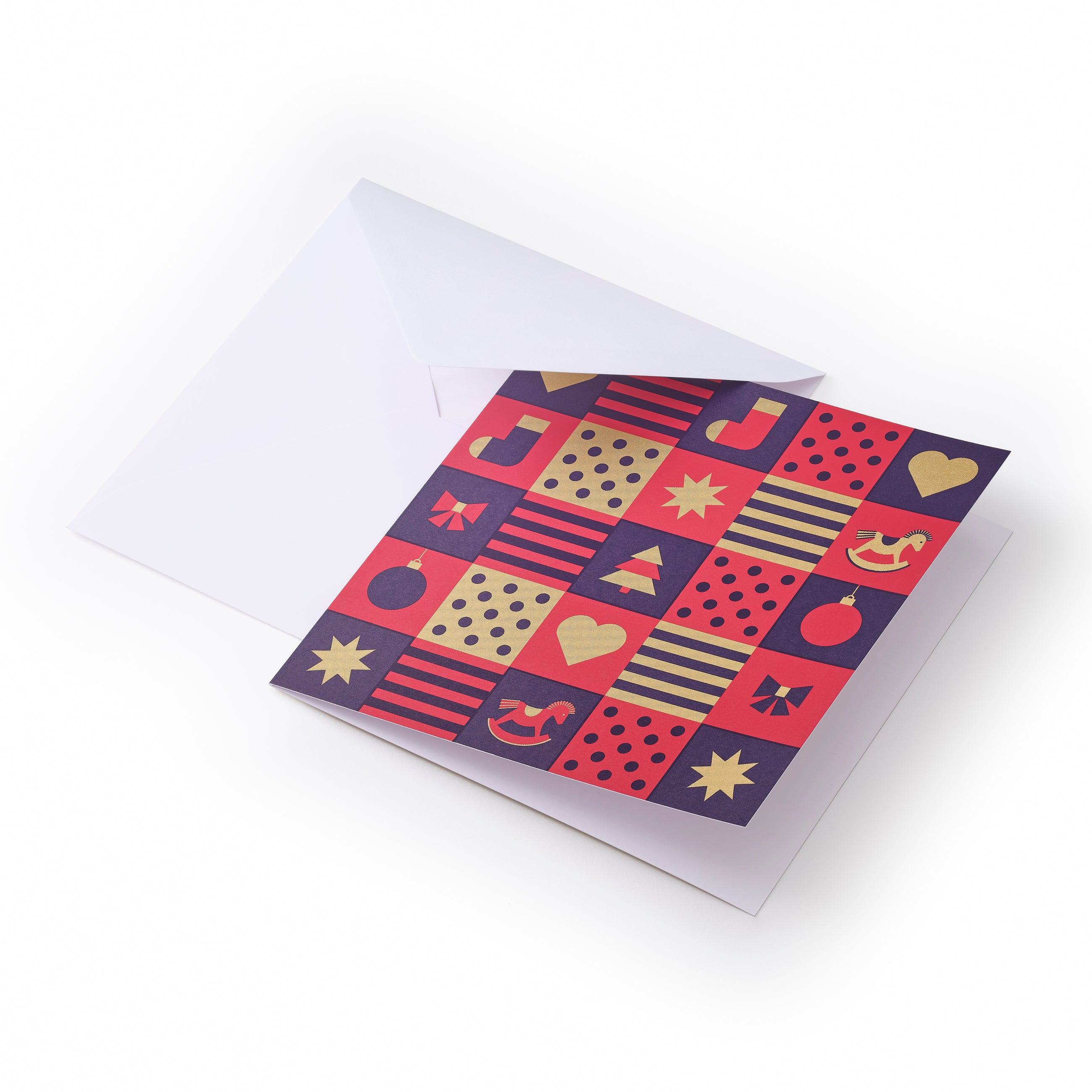 Christmas card with a checkerboard design of red, gold, and purple squares featuring festive icons like stars, hearts, musical notes, ornaments, and a rocking horse, paired with a plain white envelope.