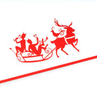 A close-up of a white Christmas card with red border, featuring a playful illustration of two reindeer pulling a sleigh with characters raising glasses.