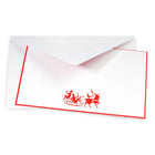 White Christmas card with red border, featuring a playful illustration of two reindeer pulling a sleigh with characters raising glasses, accompanied by a matching envelope.