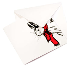 White Christmas card featuring a black sketch of a rabbit wearing a bright red scarf, paired with a plain white envelope.